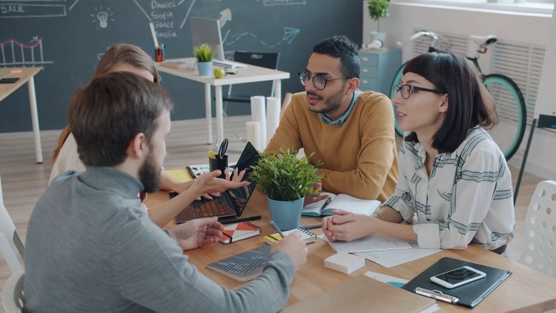 Colleagues talking and collaborating around a table in an office